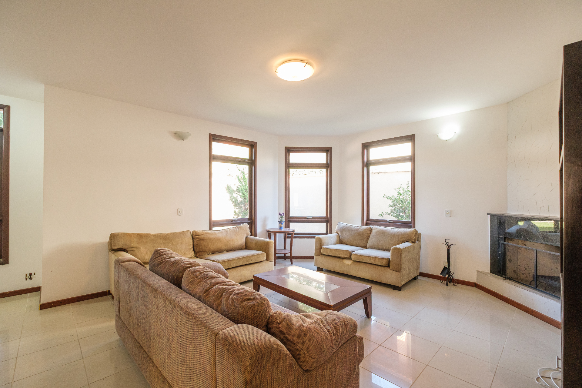 Sala de estar com lareira e três janelões