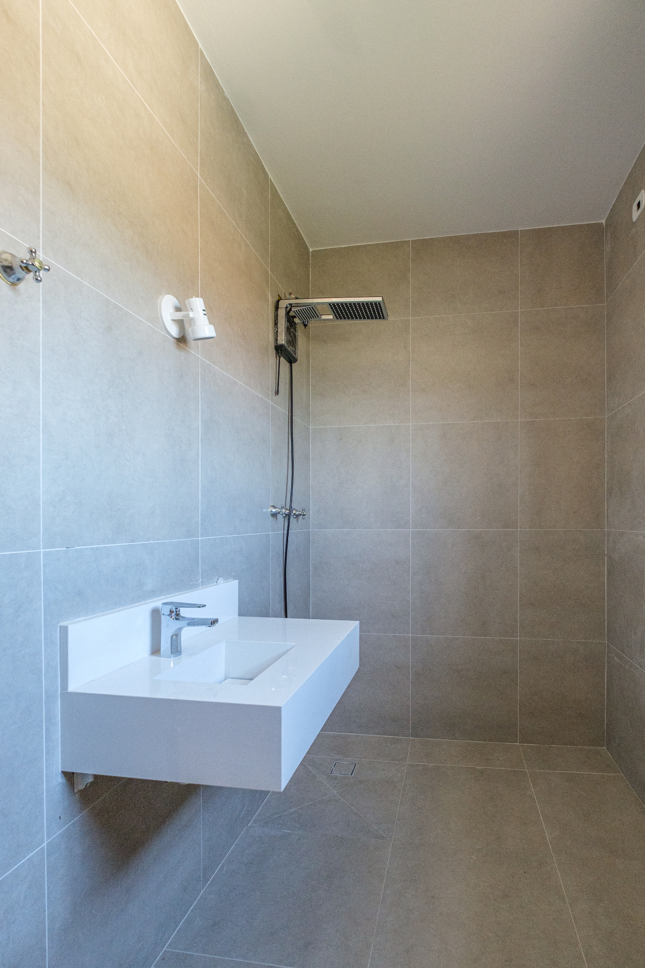 Banheiro com porcelanato cinza e ducha quadrada